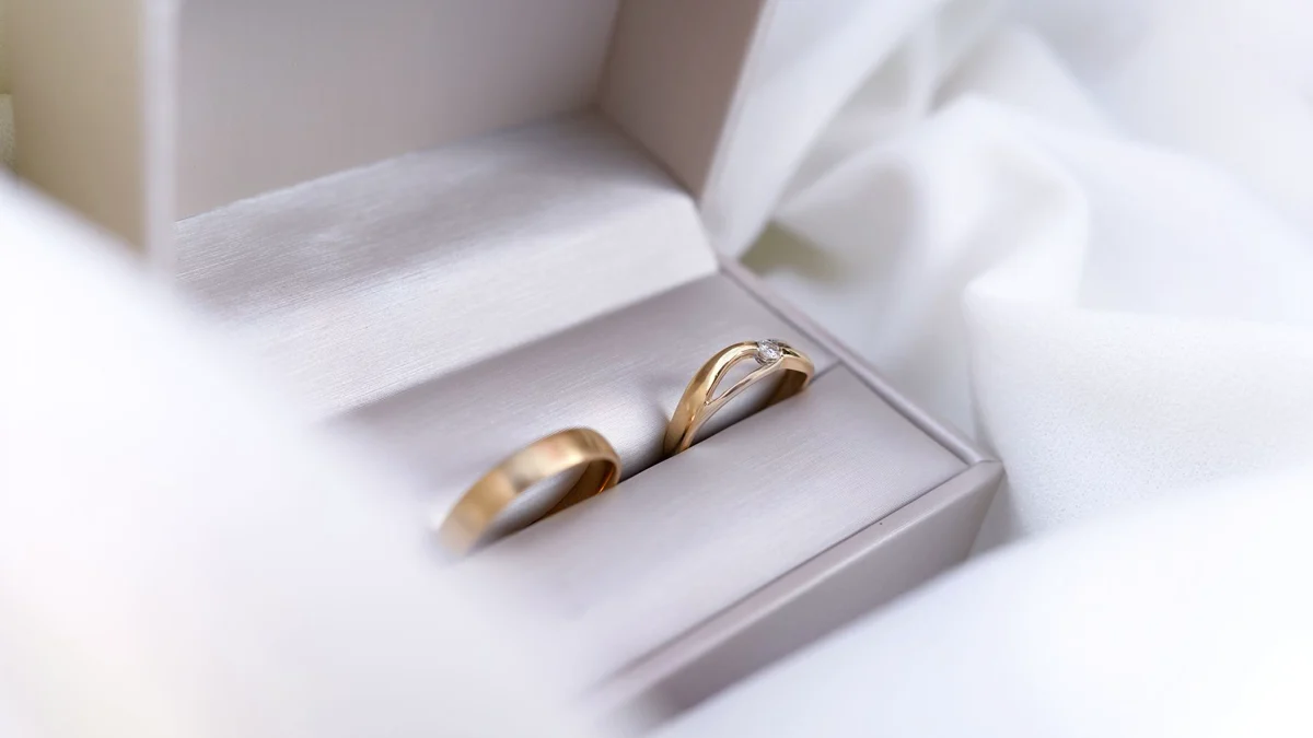 Zwei goldene Eheringe in einer hellen Schmuckschatulle