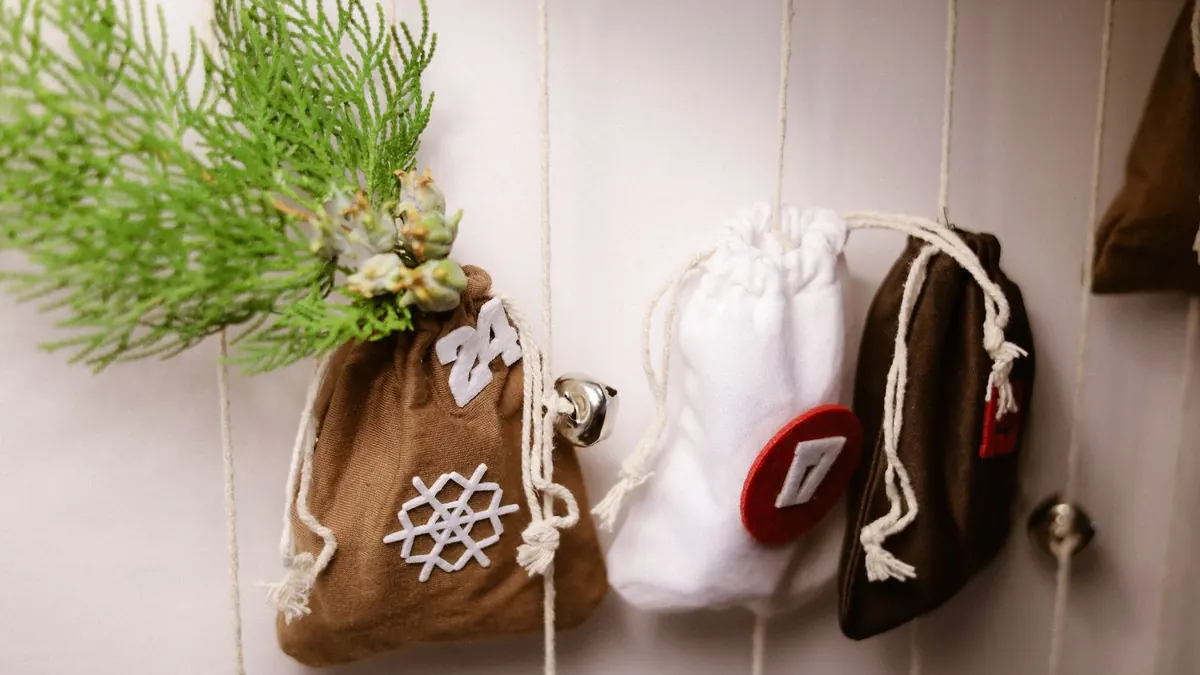 Selbst genähte Stoffsäckchen mit Zahlen hängen als Adventskalender an einer Wand