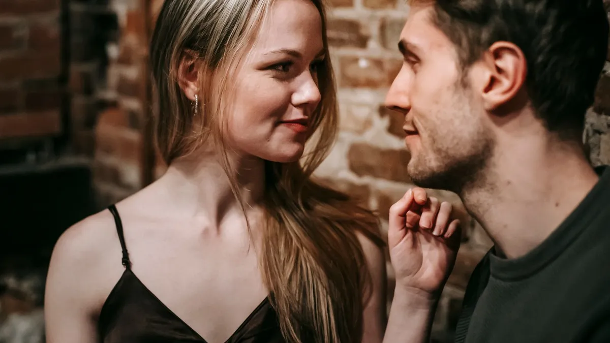 Junge Frau und junger Mann schauen sich in einer Bar lächelnd und aufmerksam an
