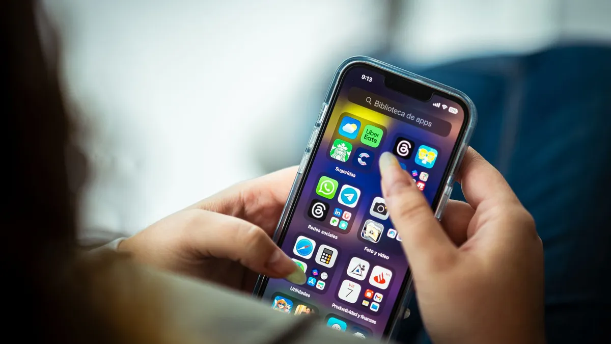 Hände halten ein Smartphone mit geöffnetem Startbildschirm voller App-Symbole