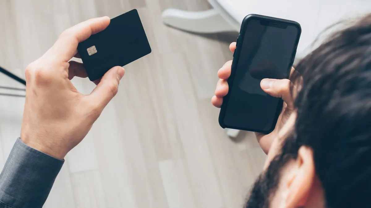 Mann hält Kreditkarte und Smartphone in den Händen, Blick von oben