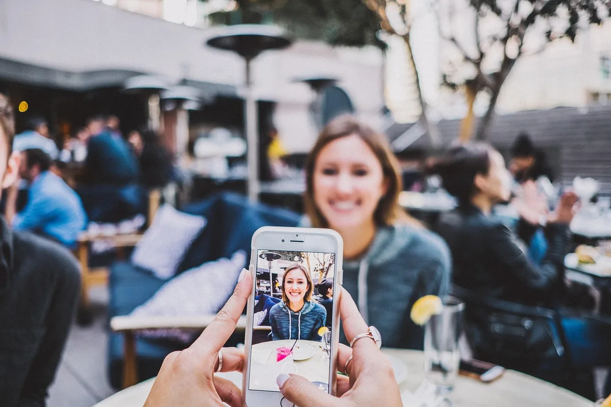 Frau mit Smartphone beim Online-Dating in einem Café