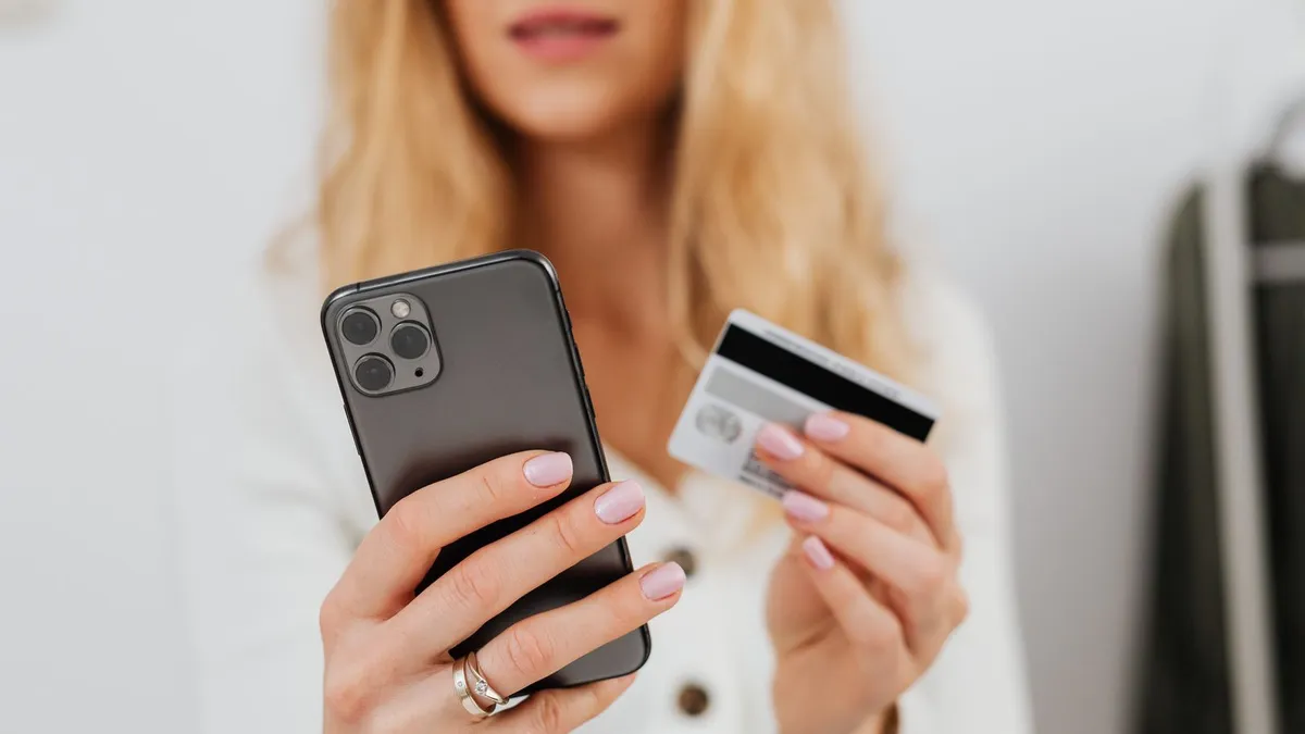 Frau hält ein Smartphone und eine Kreditkarte in den Händen