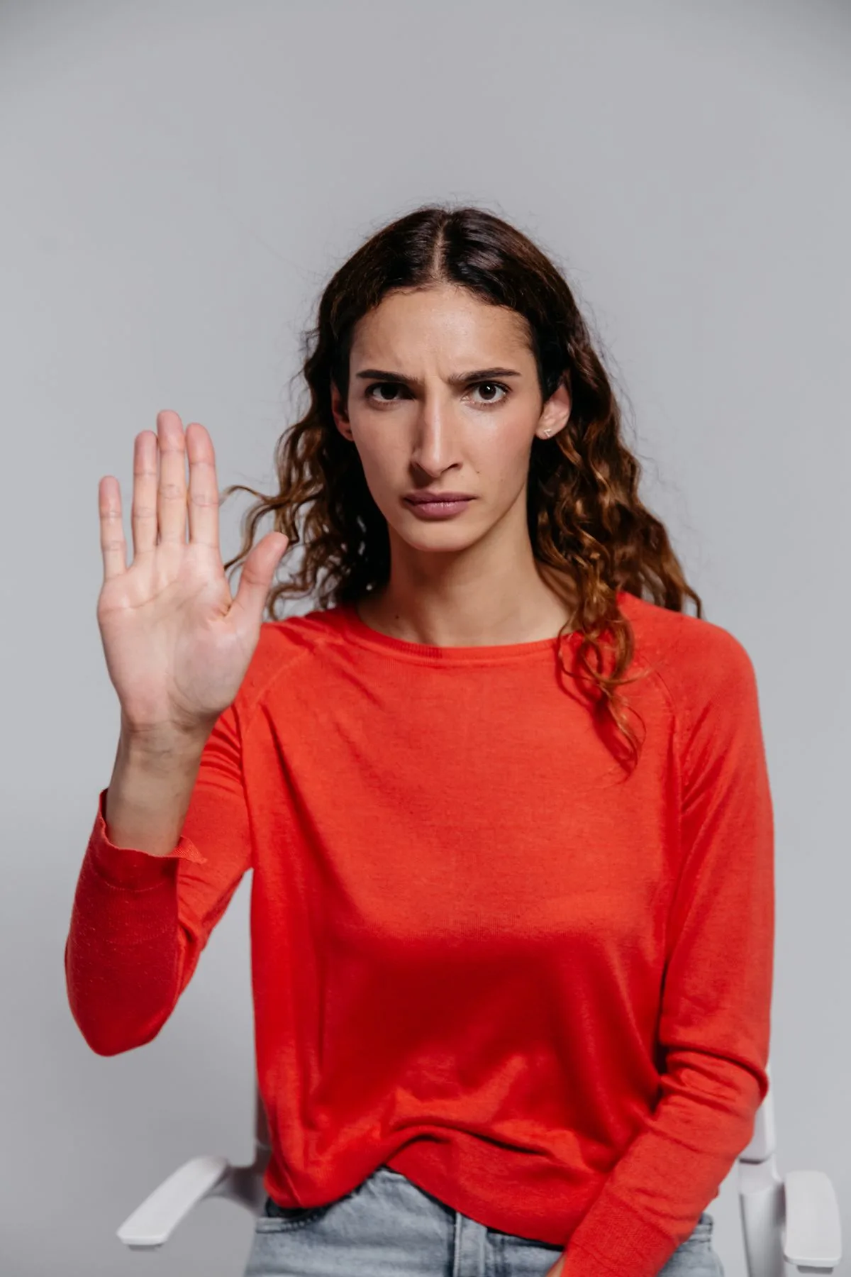 Frau in rotem Pullover hebt die Hand zu einer klaren Stopp-Geste