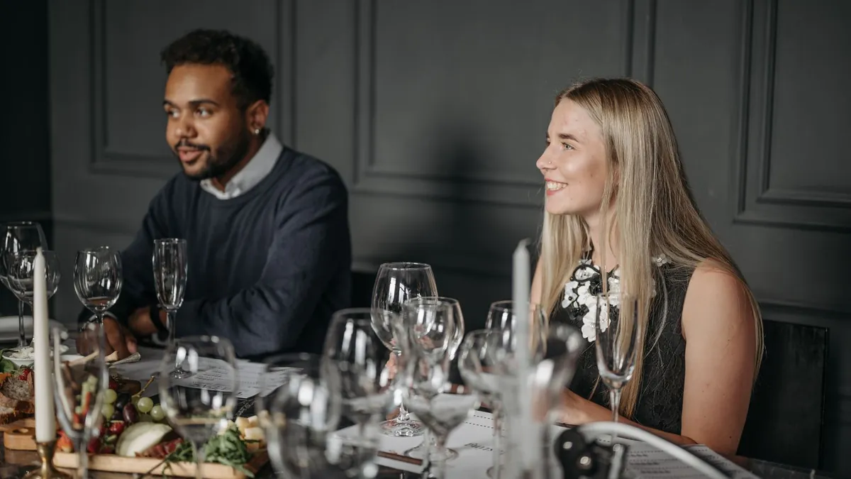 Ein Mann und eine Frau sitzen an einer festlich gedeckten Tafel mit Weingläsern und Kerzen