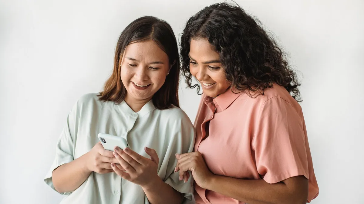 Zwei junge Frauen schauen lachend gemeinsam auf ein Smartphone