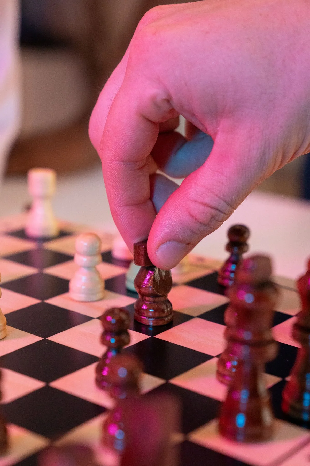 Nahaufnahme einer Hand, die einen Schachzug auf einem Schachbrett macht, in dramatischem Licht