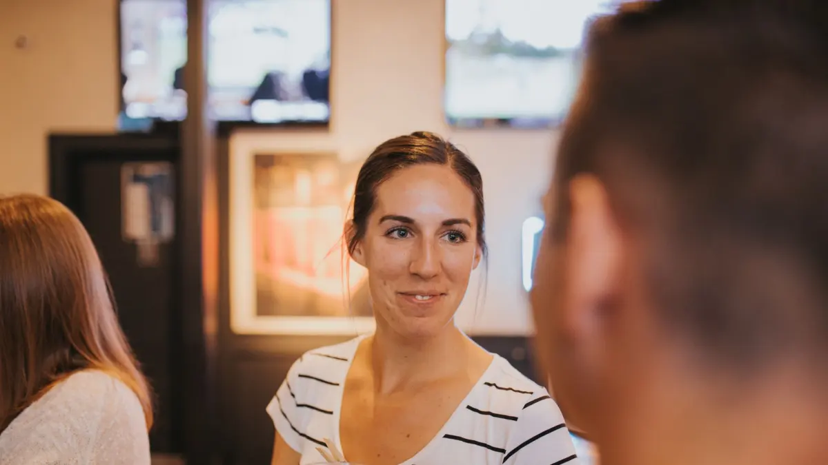 Lächelnde Frau im gestreiften Shirt im Gespräch bei einem geselligen Treffen