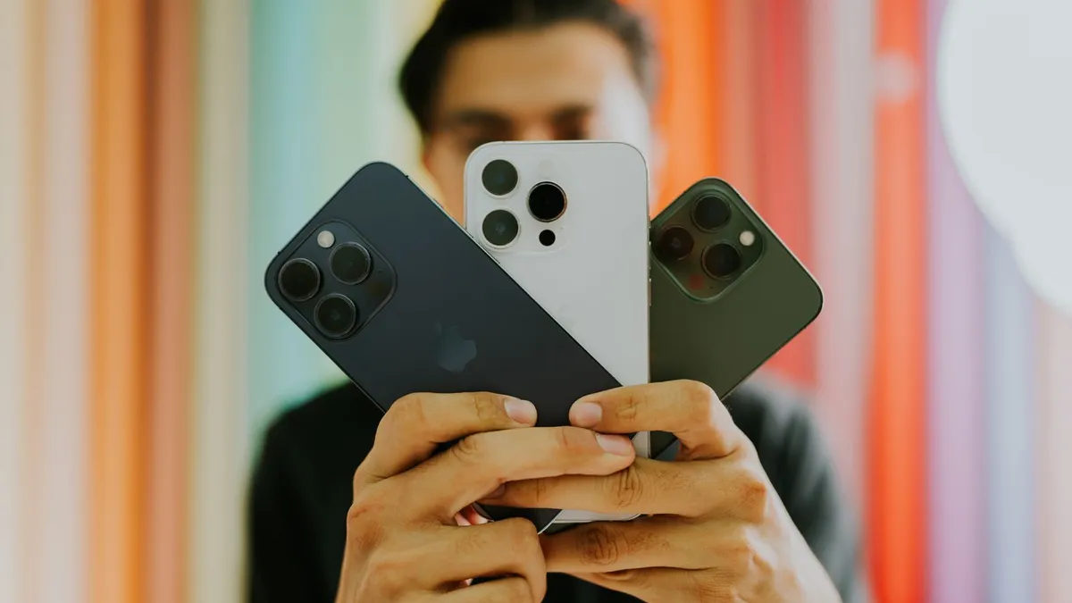 Mann hält drei Smartphones wie einen Fächer vor sein Gesicht