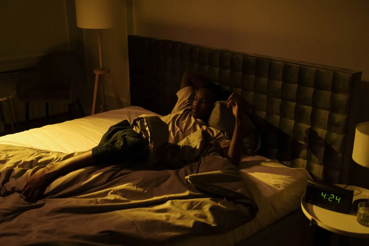 Person liegt wach im Bett und kann sich nicht bewegen — Symbolbild Schlafparalyse