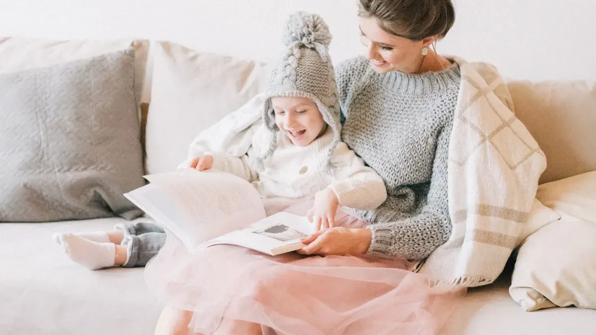 Erwachsene und Kind schauen gemeinsam ein Buch auf dem Sofa an