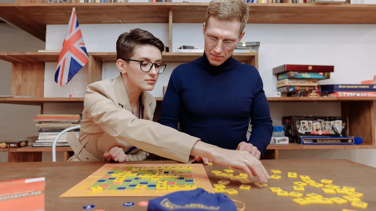 Paar spielt am Tisch ein Legespiel mit Buchstabensteinen