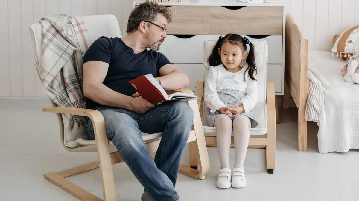 Erwachsener liest einem Kind im Kinderzimmer aus einem Buch vor