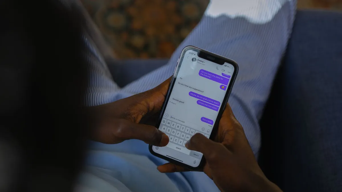 Hände halten ein Smartphone mit einem geöffneten Chatverlauf