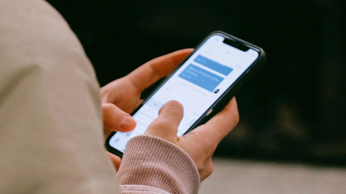 Hand hält ein Smartphone, der Daumen tippt in einem Chatverlauf