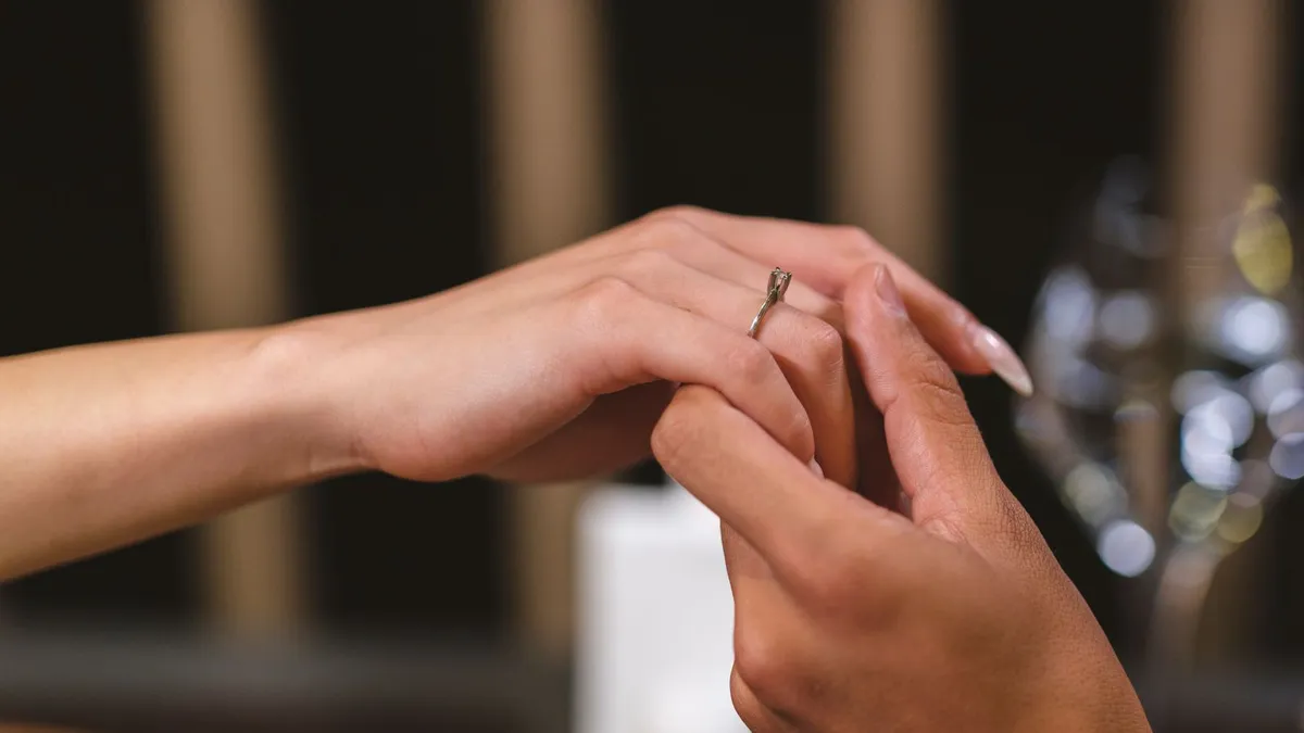 Nahaufnahme zweier Hände, bei der ein Ring an einen Finger gesteckt wird