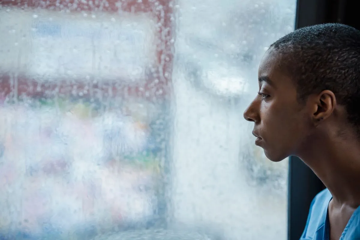 Person am Fenster mit nachdenklichem Blick — einfühlsames Symbolbild